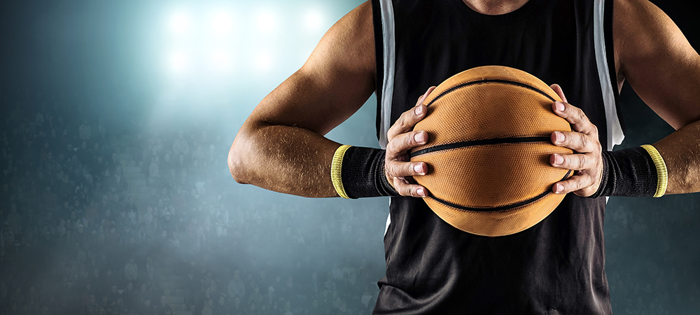 Up close torso shot of a basketball player holding a ball in hand.