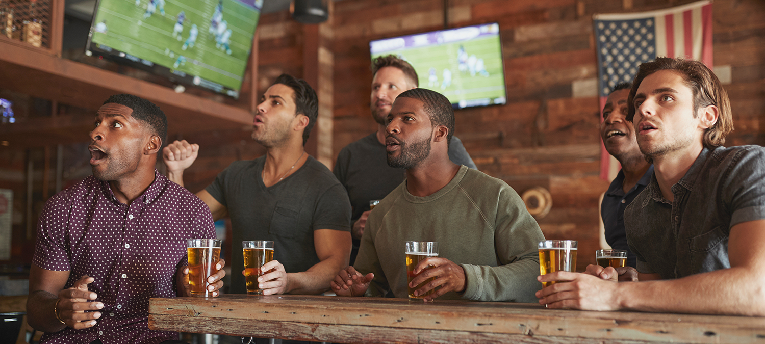 Several sports fans watching a game intensely at a sports bar.