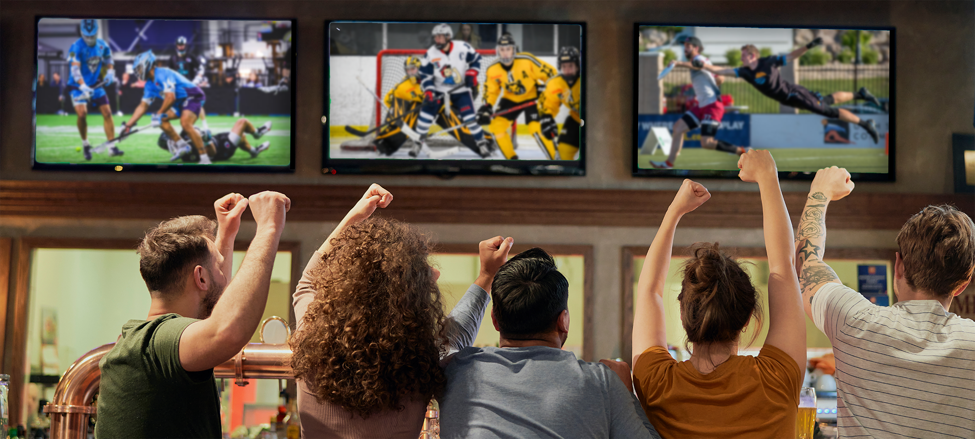 Sports fans watching professional lacrosse, professional women's hockey, and ultimate disc at a sports pub.