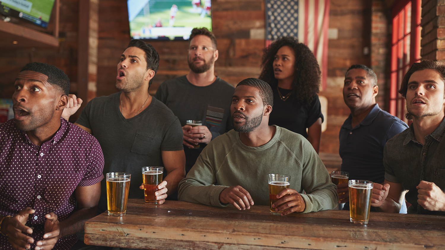Group of sports fans watching a game excitedly at a sports bar