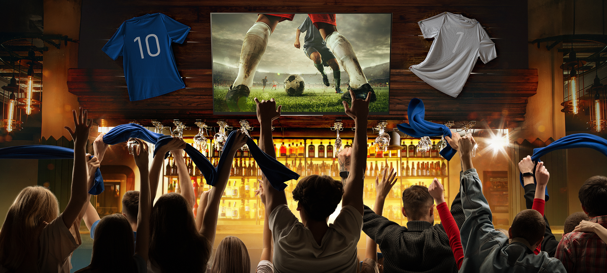 Group of sports fans and friends celebrating while watching a soccer game at a sports bar.