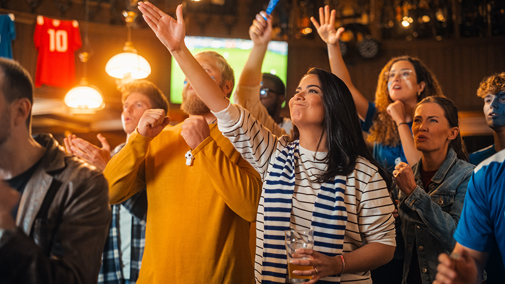 Sports fans celebrating at a sports bar while watching a game.