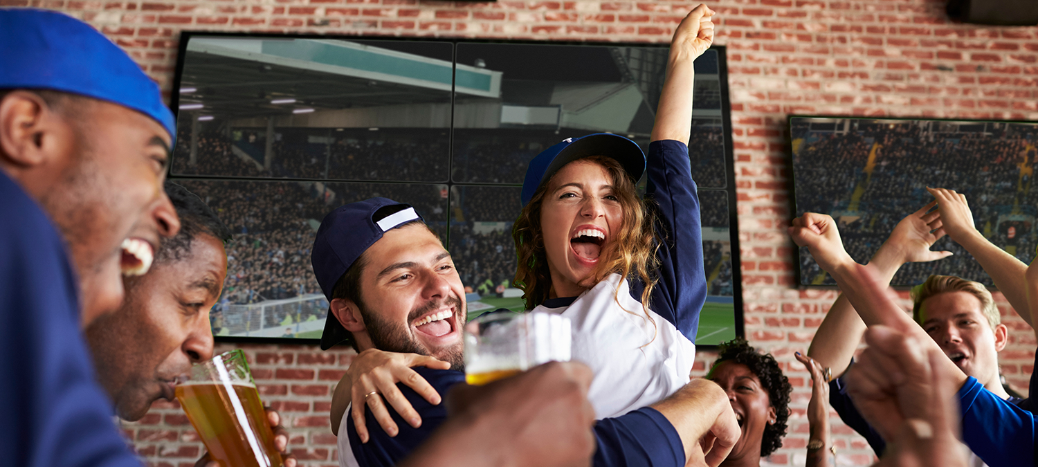 Sports fans celebrating while watching games at a local sports bar.