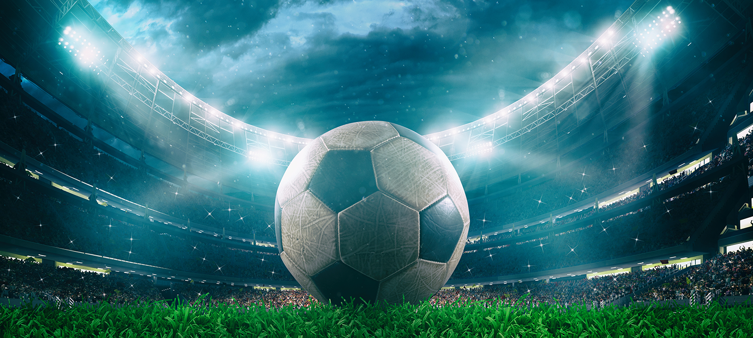 Close up of a soccer ball in the foreground with dramatic lighting and clouds in the background