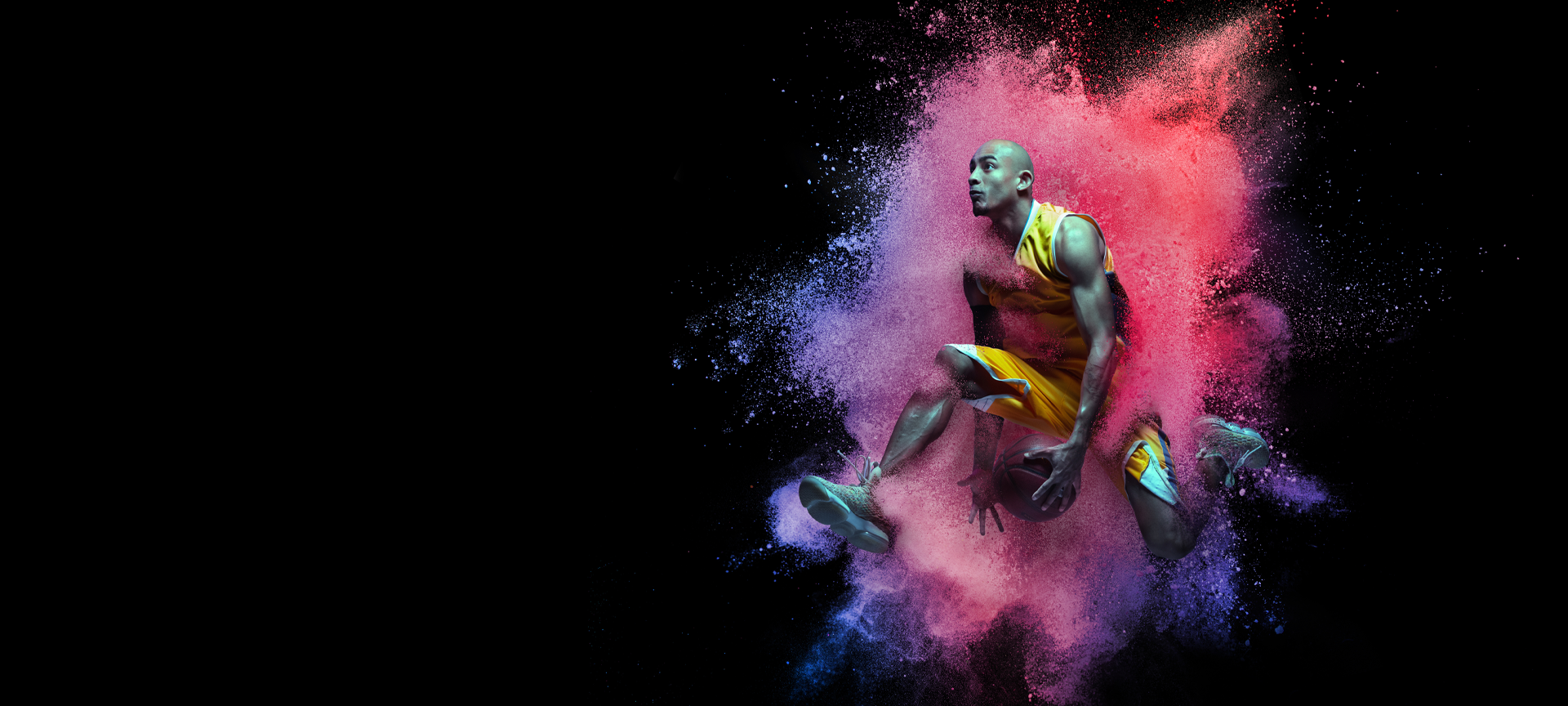 College basketball play getting ready for a slam dunk, exploding through color powder splash against a black background